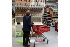 Man in a grocery store looking at refillable options.